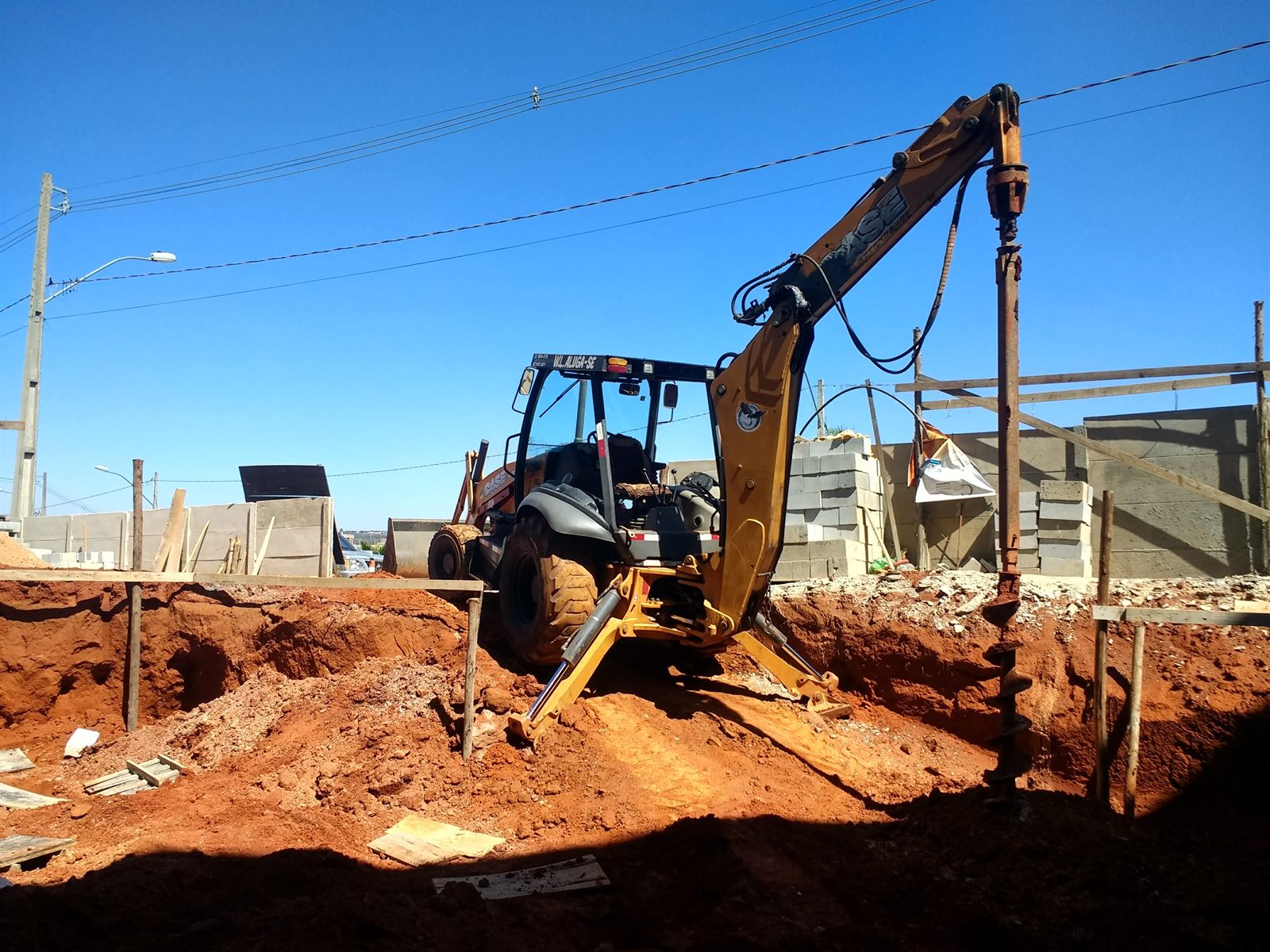 Retroescavadeira realizando nivelamento e limpeza de terreno