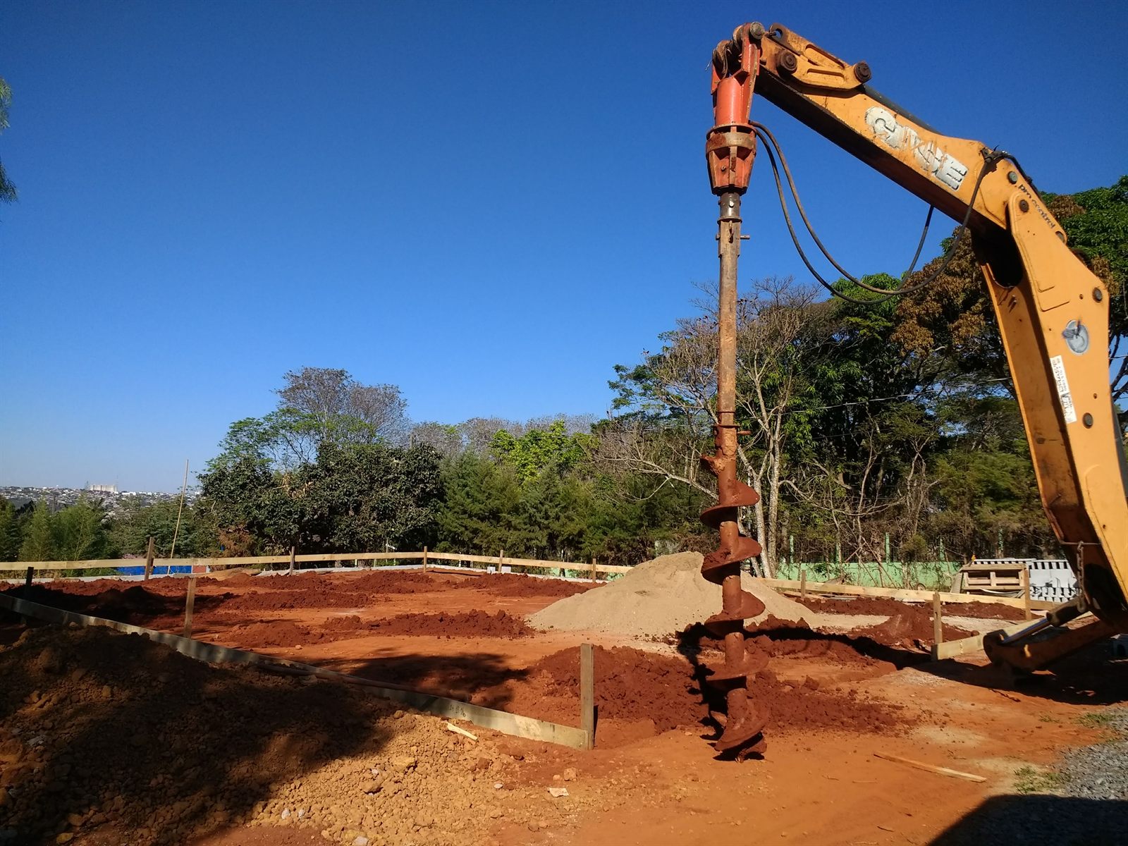 Retroescavadeira nivelando platô de terra para construção civil